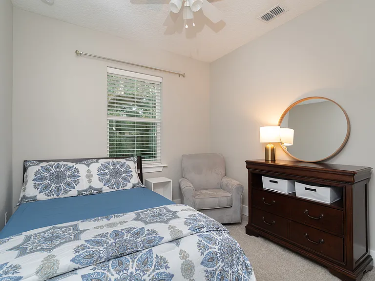 Unwind in style! This beautifully lit bedroom features an ultra-comfortable bed with premium linens, soft accent lighting, and a charming round vanity mirror.