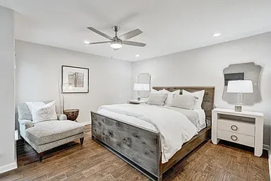 Primary bedroom plenty large enough for king bed and seating area. Windows let in natural light in day, and blackout shades provide dark room for restful sleeping.