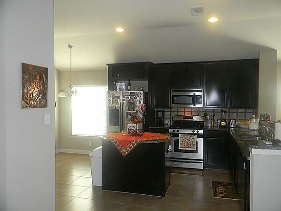 THE KITCHEN HAS ALL STAINLESS APPLIANCES, AN ISLAND AND BREA