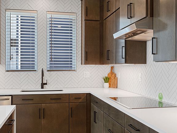 Modern kitchen in Cascade Village with dark cabinets, white countertops, a herringbone tile backspla