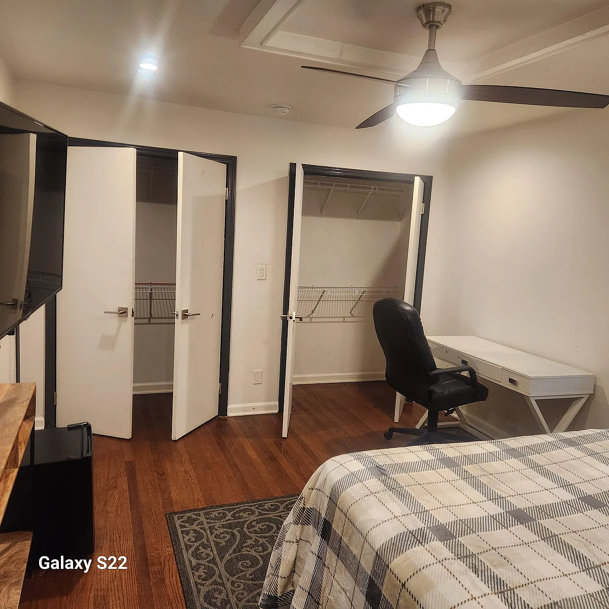 Bedroom with hardwood floors, ceiling fan, a work desk area, and two closets with shelving for convenient storage. - Williamson Dr