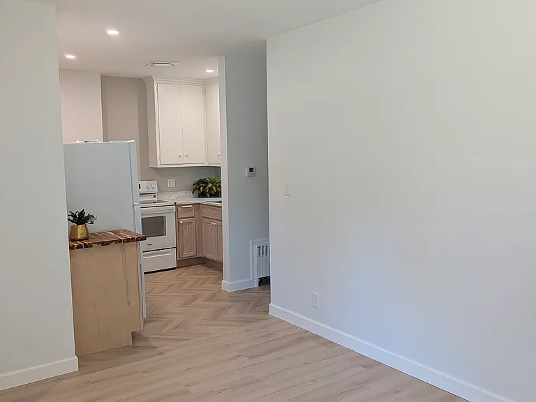 Kitchen with chevron floor leading into living area.