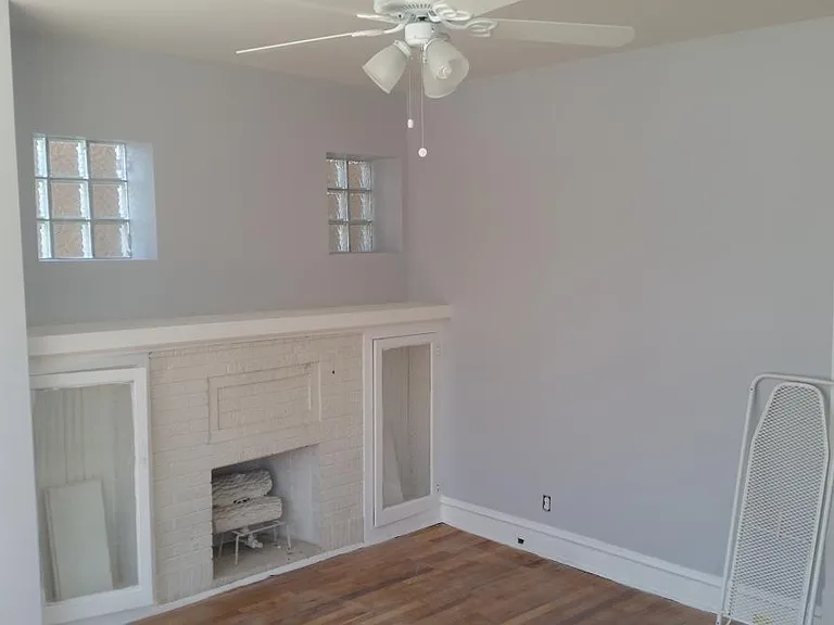 Living room view of faux fireplace and hallway leading to the dining room.