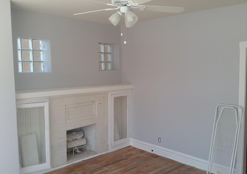 Living room view of faux fireplace and hallway leading to the dining room.