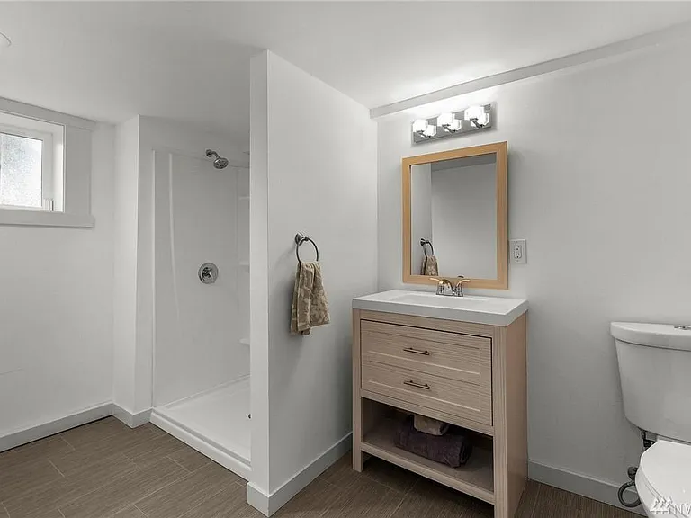 The beautifully updated lower-level full bathroom features a walk-in shower, modern vanity, and stylish finishes, offering comfort and convenience for guests or private living.