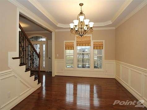 Elaborate crown moldings accentuate the raised trae ceiling. Wainscoting, chandelier & hardwood flooring are also included in this formal dining room.