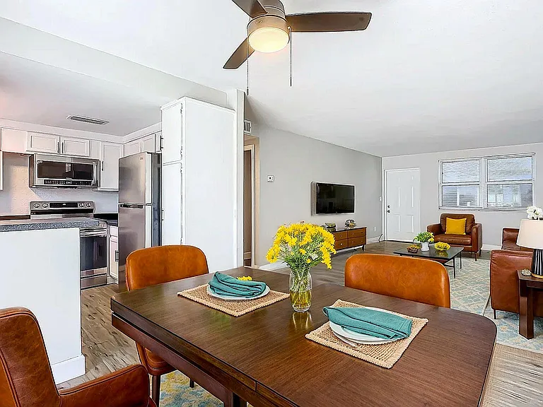 Bright and inviting open-concept living space featuring a modern kitchen, elegant dining area, and cozy living room with stylish leather seating.
