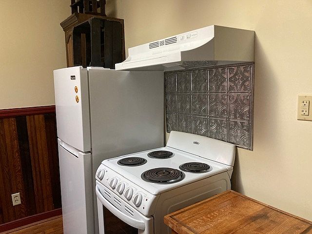 This is the left side of the kitchen cook area. It features a cutting table, full range and oven and a refrigerator/freezer.