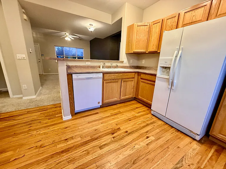 Another view of kitchedn area showing cabinets, hardwood flooring and main level view of the living room.