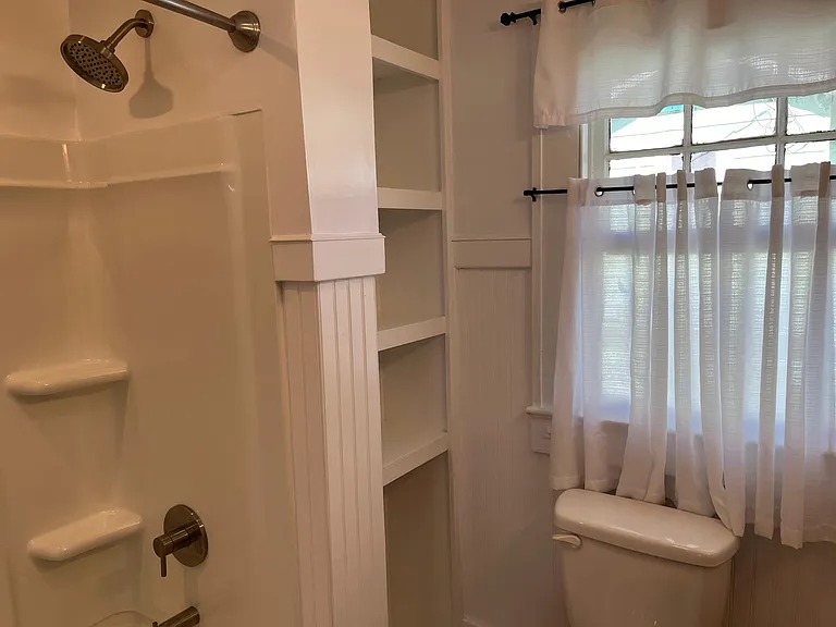 Shelving built in to accommodate additional bathroom storage with convenient area for small hamper or litter box.