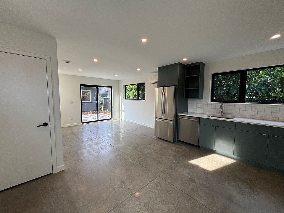 Open floor plan with full kitchen, dishwasher, concrete floors. Washer/dryer units behind door.