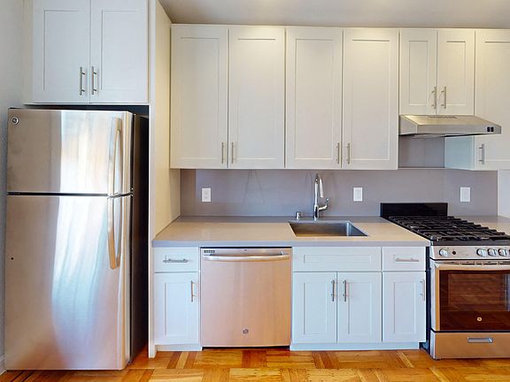 Kitchen with multiple cabinets, refrigerator, stove, range hood, and sink