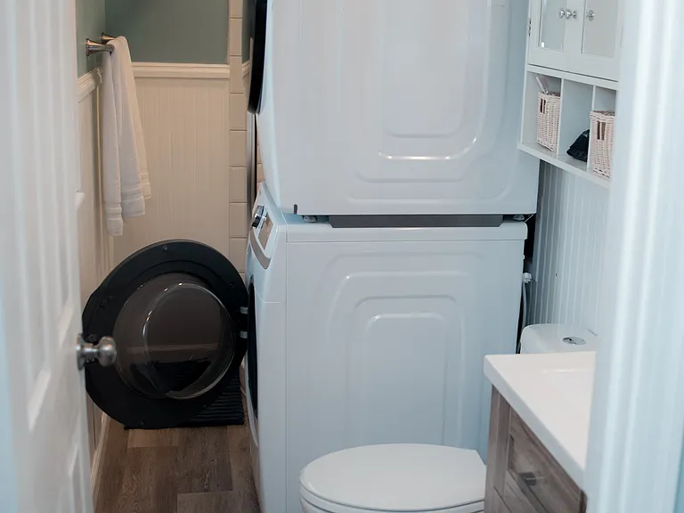 Bright vanity area with a wood-toned cabinet and extra storage for your toiletries. Washer and dryer located here.