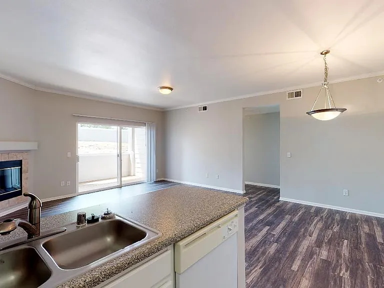 Apartment living room with wood-style flooring and patio or balcony in select homes.