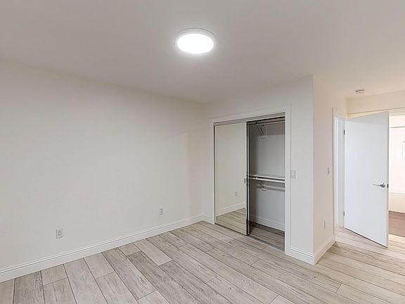 Bright bedroom with wood-like floor and a closet with mirror
