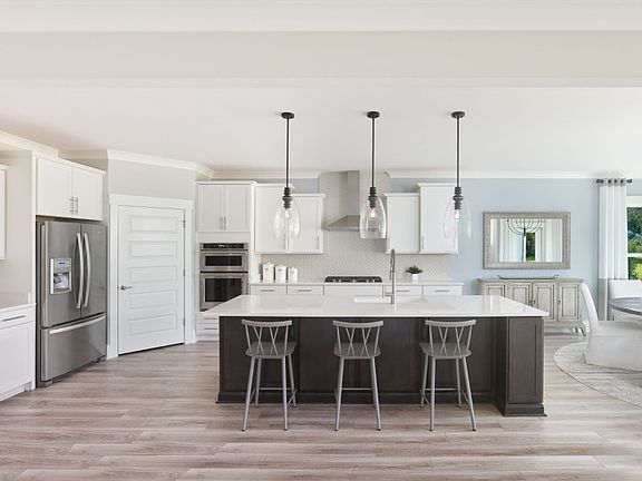 Large kitchen area with an island centered underneath pendant lighting.
