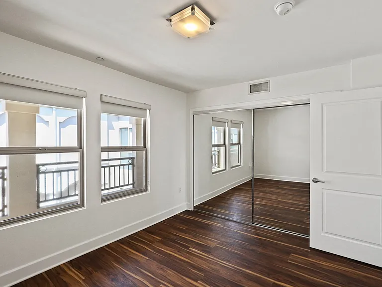Bedroom with Mirrored Closet, Vinyl Flooring, and Double Windows