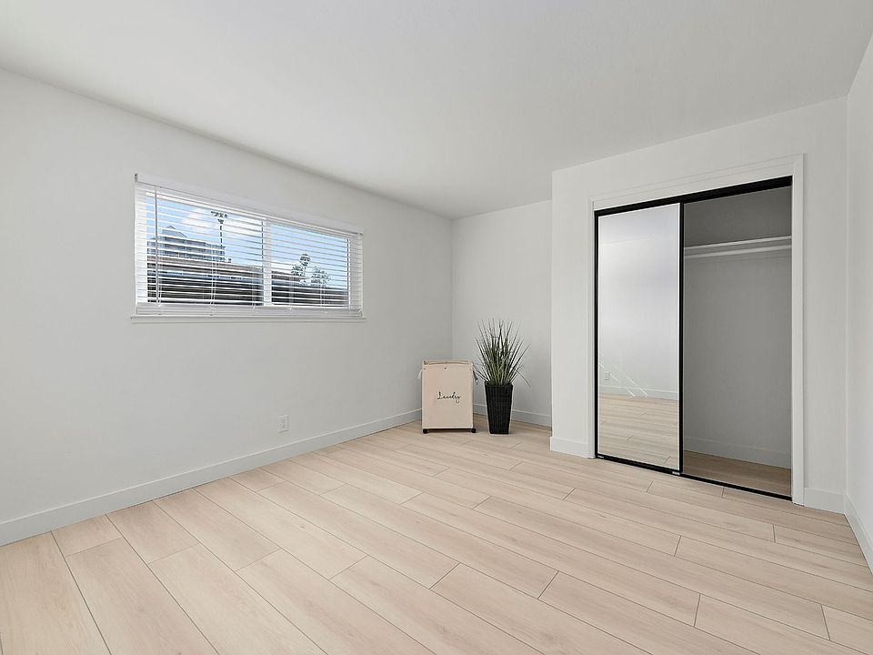 A generously sized bedroom with mirrored closet doors that add brightness and a sense of expanded space.