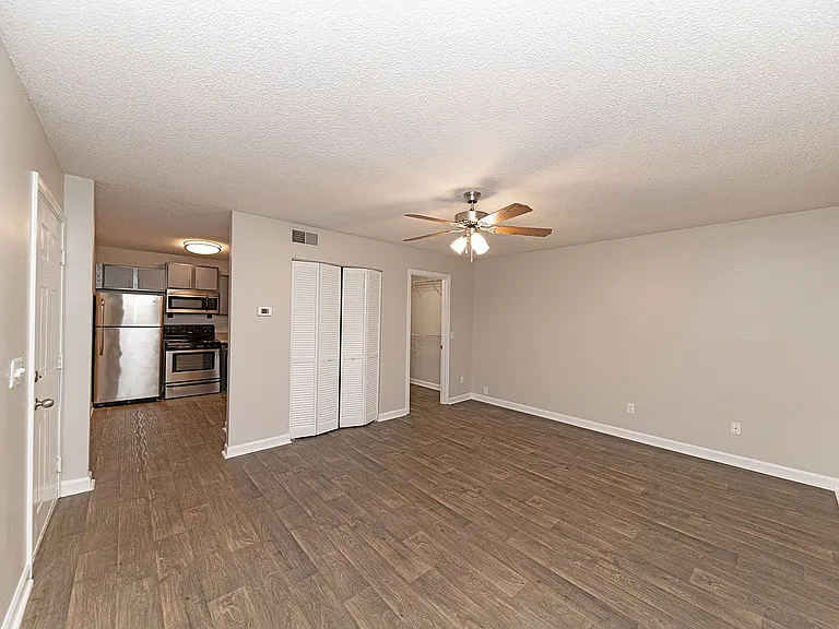 Spacious living room with hardwood-style flooring & ceiling fan