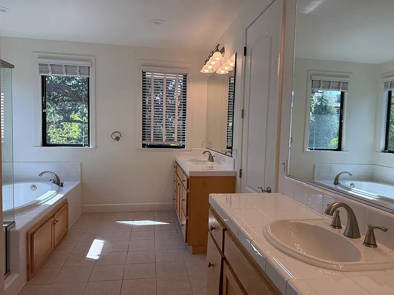 In-suite bathroom with 2 sinks, a whirlpool bathtub, a shower stall with glass enclosure and a second walk-in closet.