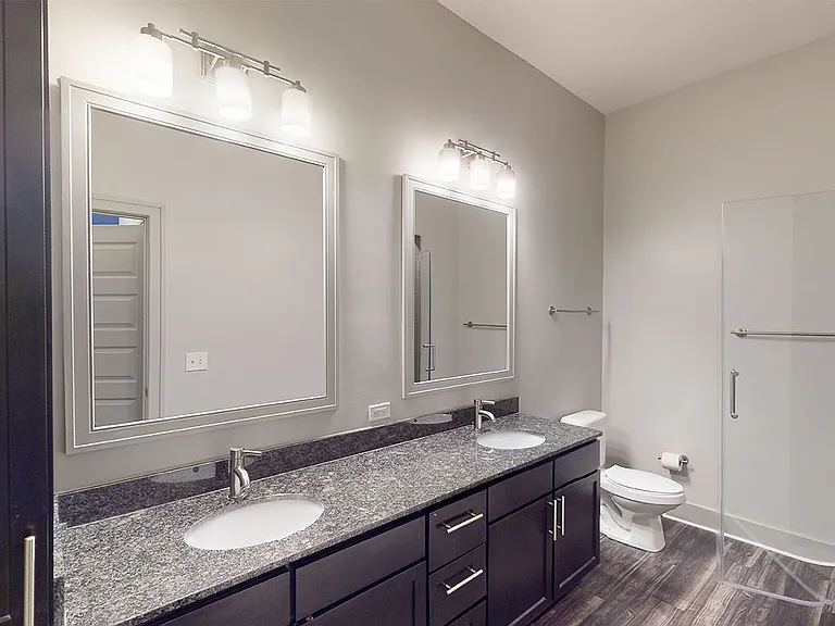 Apartment bathroom with wood-style flooring and double sinks.