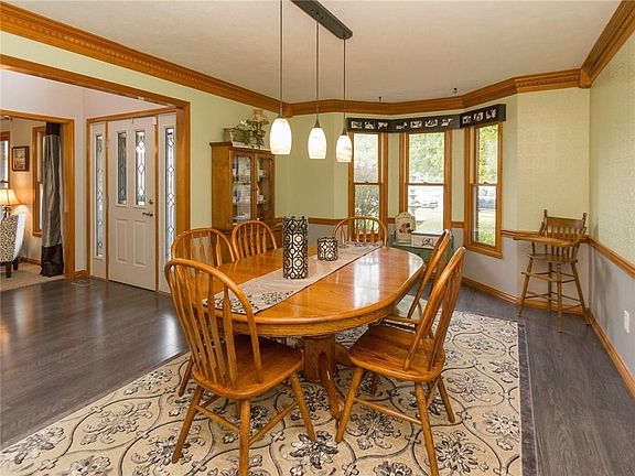 Dining room with crown molding, updated light fixture, bay window, and new laminate flooring.