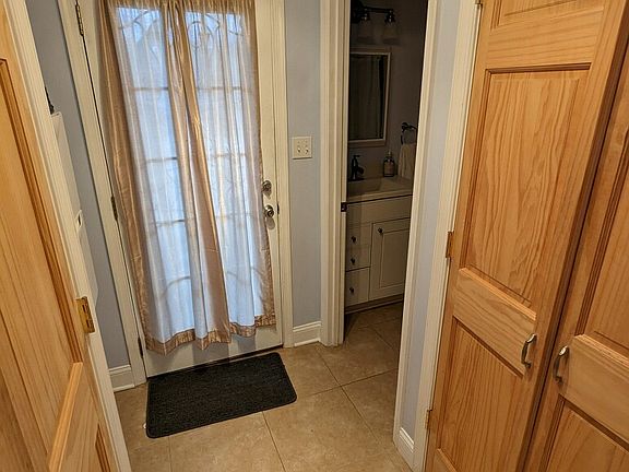Hallway to parking pad, coat closet, and first floor full bathroom.