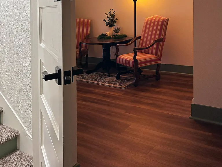 Apartment front door (at left) with view of furnished, shared lobby area in background.