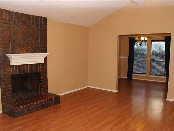 Family room with laminate wood floors and a wood burning fireplace.