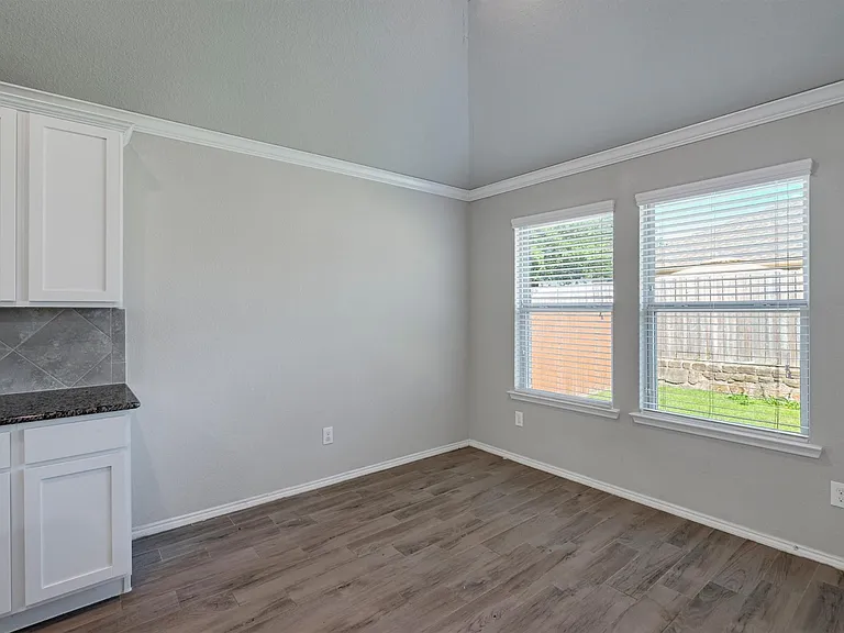 Room featuring wood-finish flooring, crisp white baseboards, and crown molding