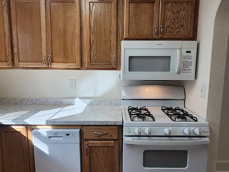 Kitchen - dishwasher and new gas range with over-the-range microwave oven hood.