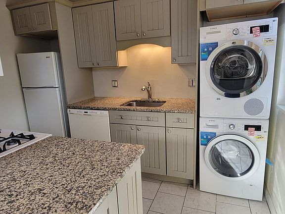 Kitchen with granite counters, gas stove, tile floor and Bosch washer and dryer.