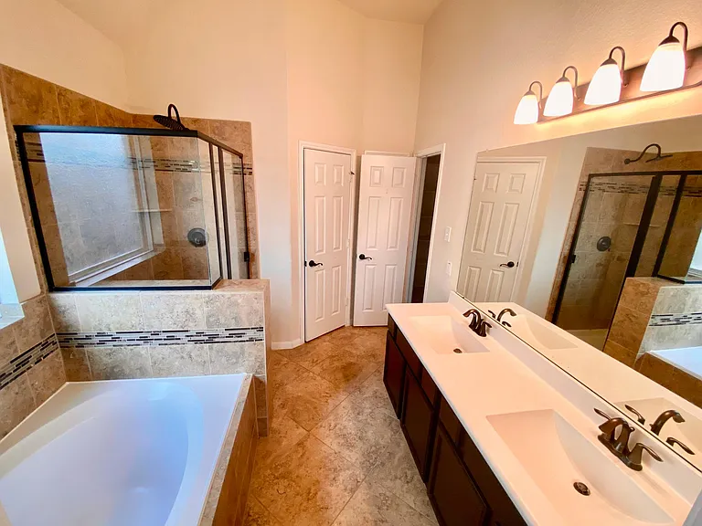 Primary bathroom with dual vanity, separate tub and shower, nice tiling and fixtures
