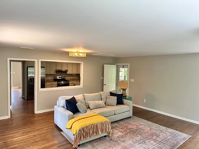 Large sunny living room off of the kitchen with a door that leads to huge deck.