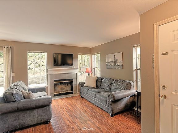 Spacious living room with wood burning fireplace. Front door is shown on the right.