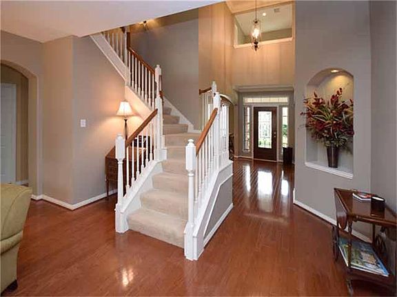 A two-story foyer and beautiful staircase are enhanced by the extensive hardwood flooring extending 