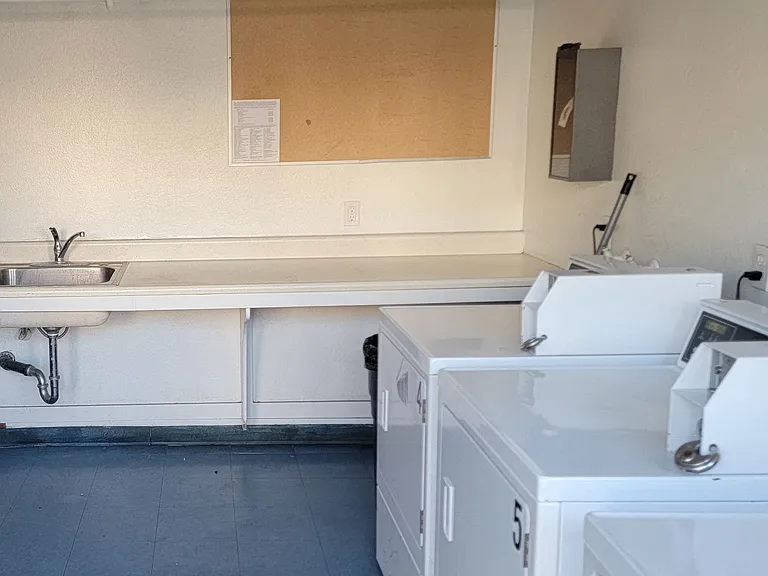 Laundry room near pool with washers, dryers, sink, and folding area at Presidio Villa Apartments.
