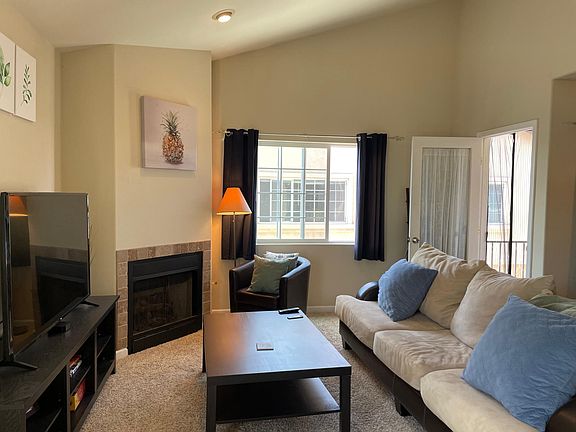 Living room with vaulted ceiling and fireplace. Balcony access