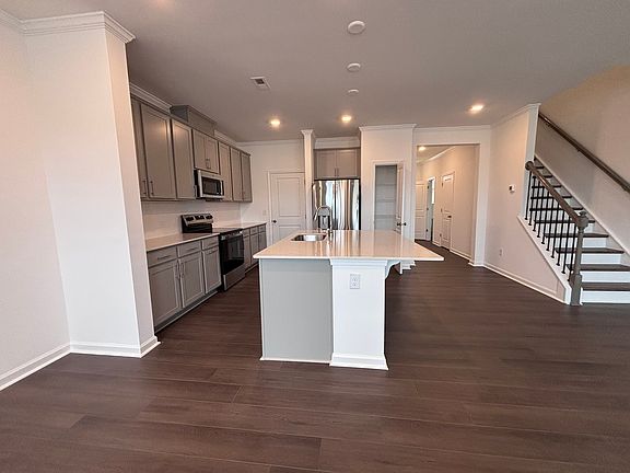 Modern kitchen with granite countertops, tile backsplash, stainless steel appliances, and large center island.