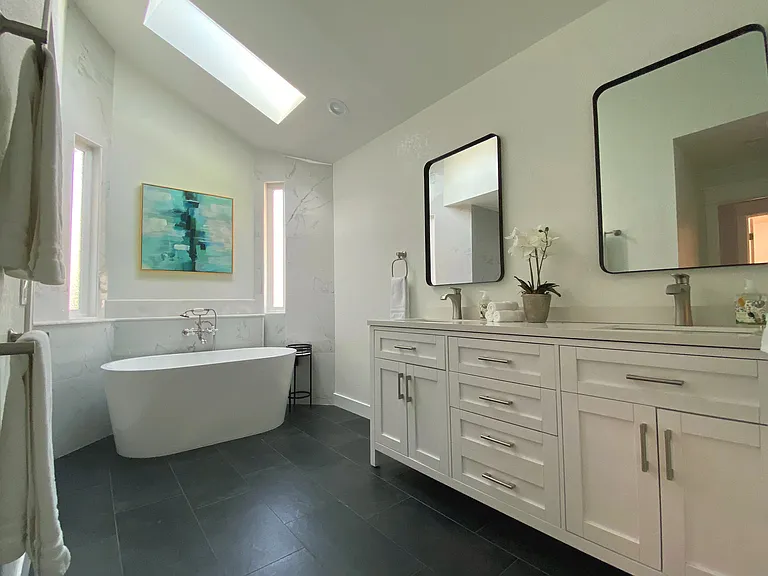 Relax in the spa-style master bath featuring a luxurious soaking tub under a skylight and a sleek, walk-in curb-less shower _ your private retreat awaits.