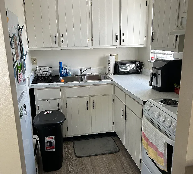 Kitchen area, stove on right, frig on left, sink ahead with disposal underneath, window looking out