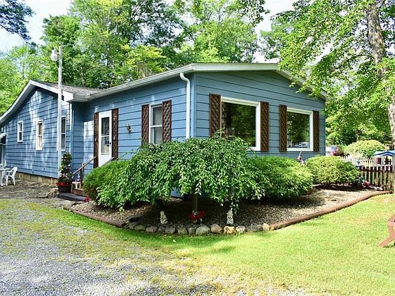 Another view of the L-shaped ranch styled home. Clean landscaping and trees create a cozy atmosphere.