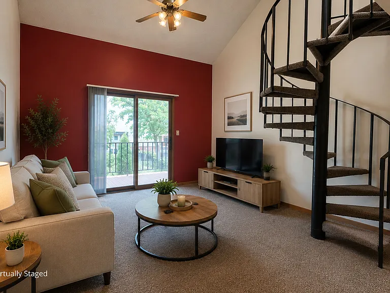 Two-story apartment living room with a loft layout, carpeted flooring, a spiral staircase, and ceiling fan,.