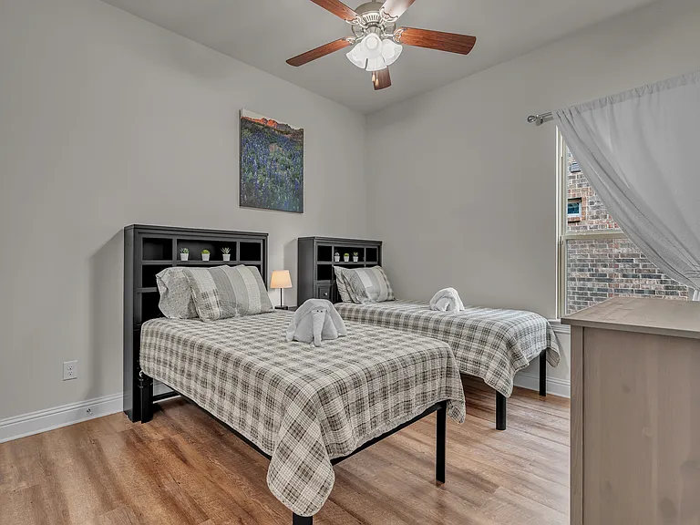 3rd guest bedroom has two twin beds, walk in closet, ceiling fan, lamp, side table and dresser