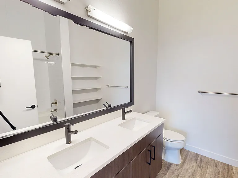 Apartment bathroom with wood-style flooring and double sinks.