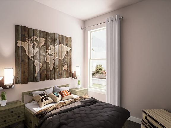 A cozy bedroom with a large wooden world map on the wall, a comfortable-looking bed with a gray comf