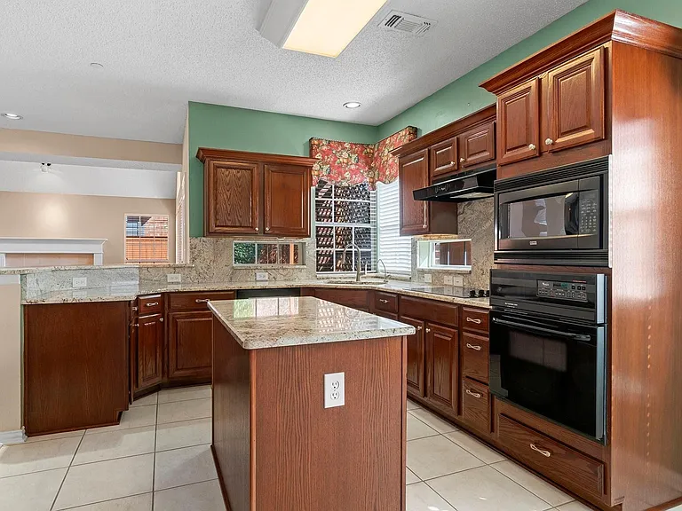 Kitchen featuring wood-finish cabinetry, granite countertops, and light-toned floor tiles