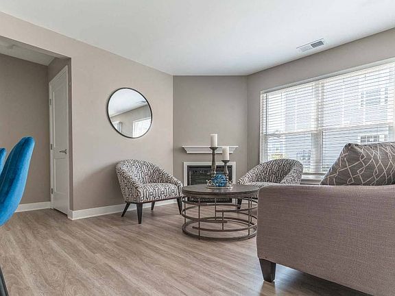 View of living area of great room showing fireplace, large windows, plank flooring, and foyer