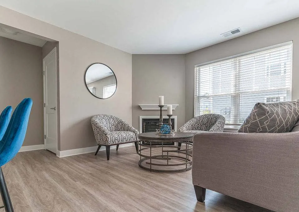 View of living area of great room showing fireplace, large windows, plank flooring, and foyer