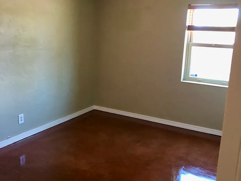 Empty bedroom that had king size bed in photo. The window over looks the courtyard patio.